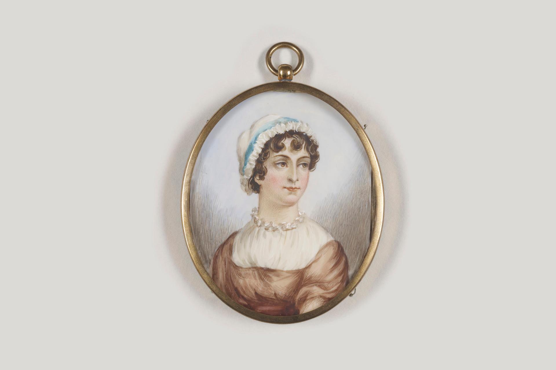 An oval portrait miniature of a woman with curled brown hair, wearing a white bonnet, pearl necklace, and brown dress, set in a gold frame with a loop at the top.