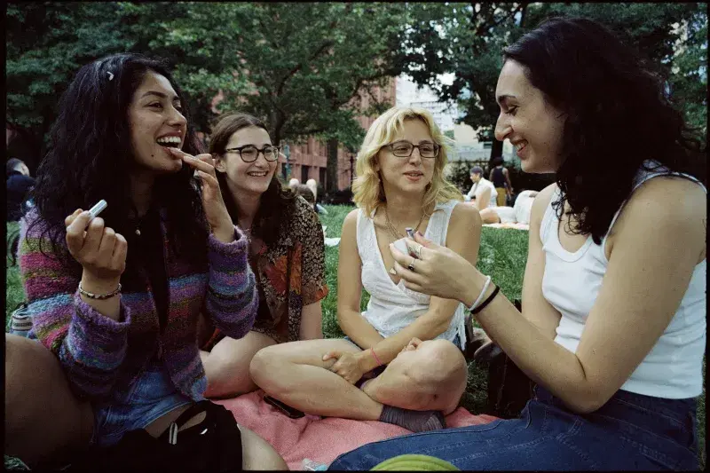 A group of people applying makeup and hanging out at Washington Square Park in Manhattan