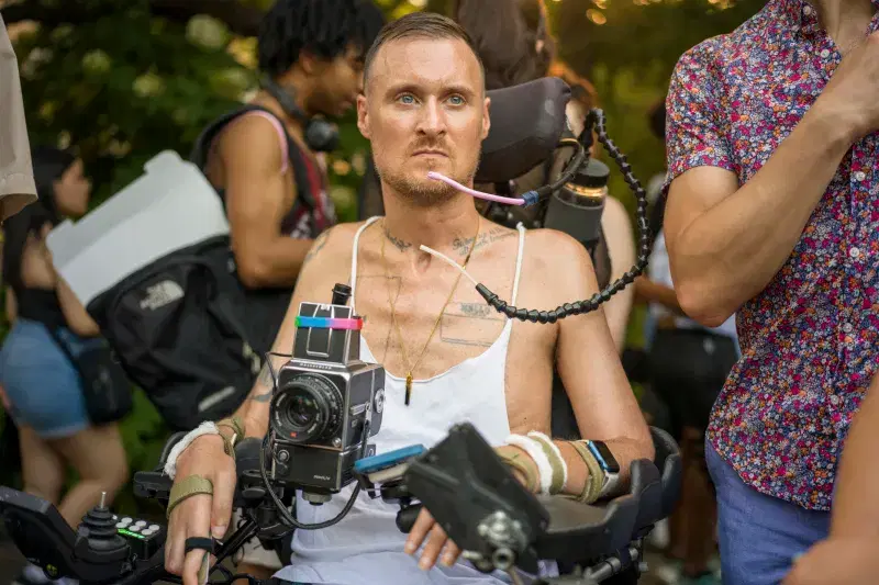 Photographer Robert Andy Coombs in his wheelchair with camera