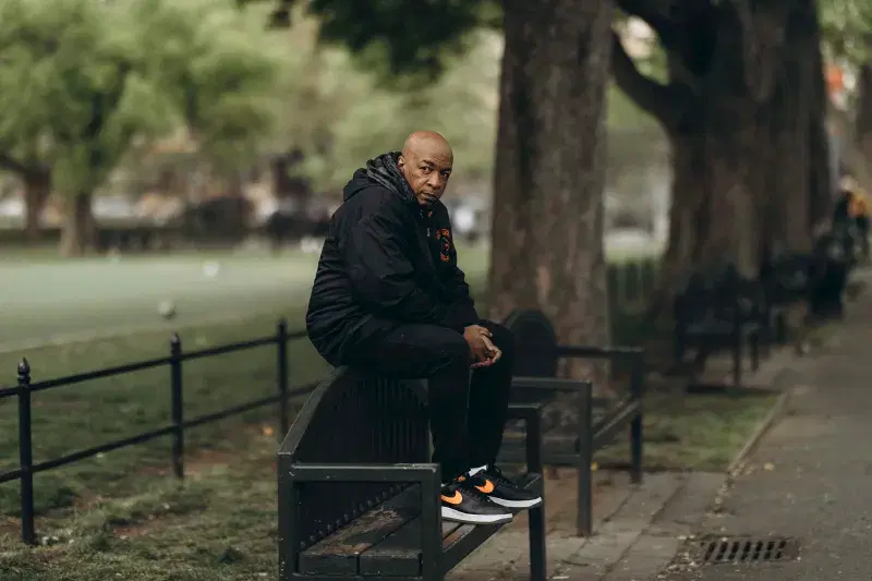 Portrait of Ralph McDaniels sitting on a bench at Rufus King Park in Queens