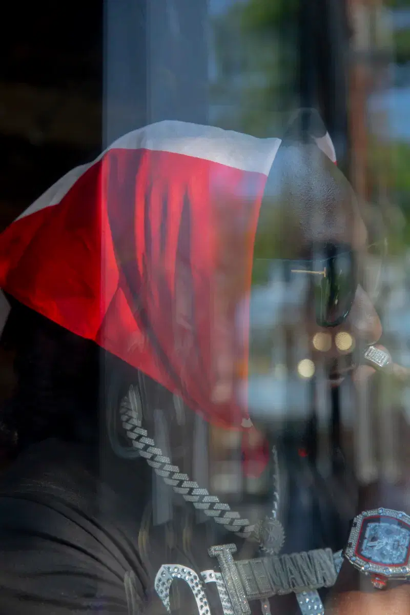 Person wearing flag as a headpiece looking through glass