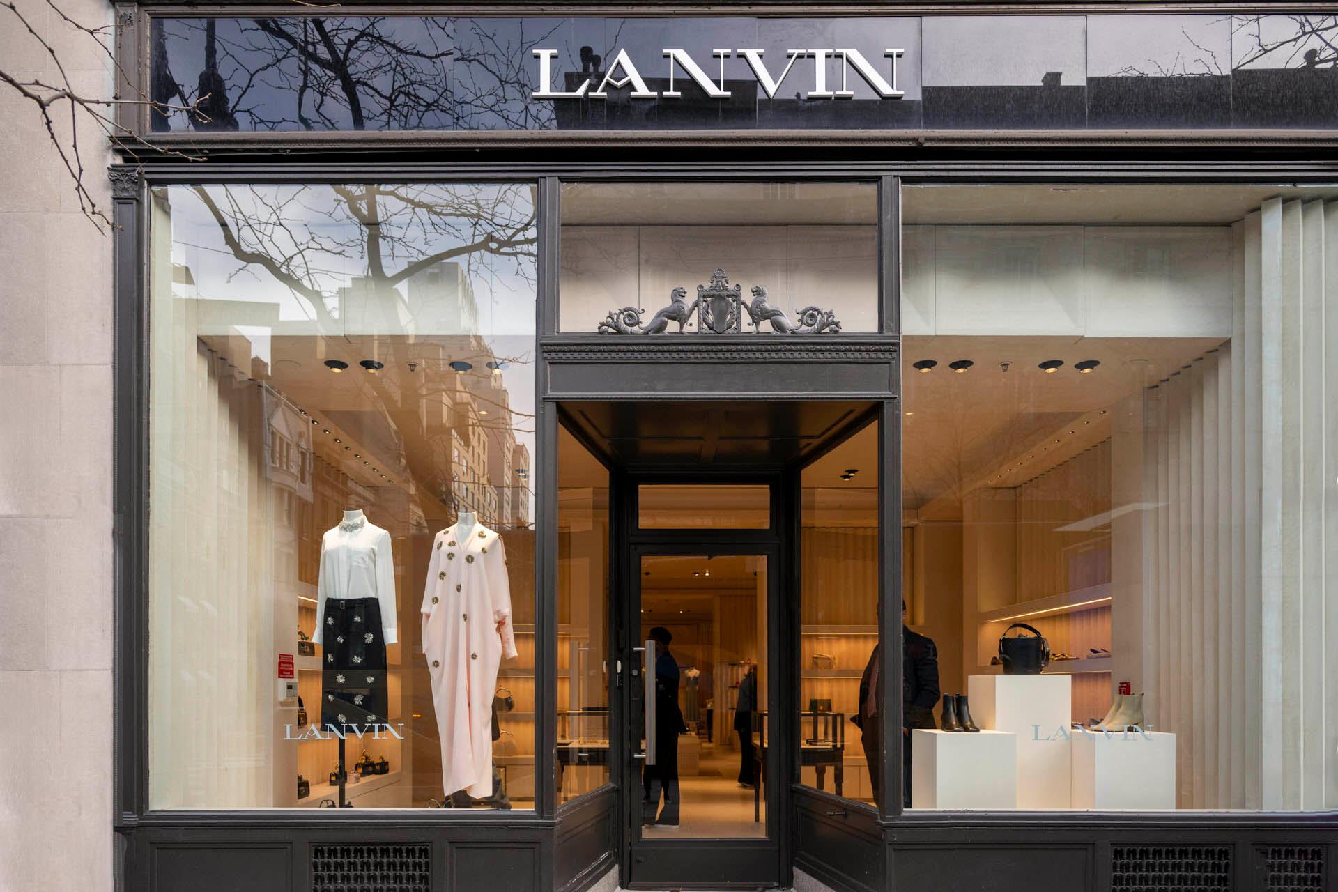 Storefront of a boutique with "LANVIN" sign above. Large windows display elegant mannequins wearing sophisticated clothing. Inside, shelves and racks showcase more fashion items. The exterior includes a minimalist and modern design.