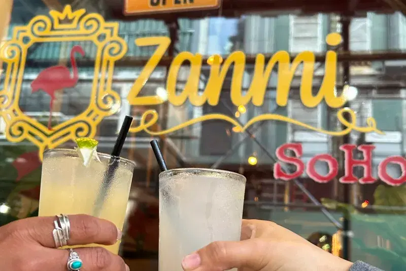 Hands holding drinks outside of Zanmi