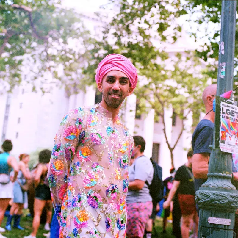 Person wearing colorful outfit and pink headpiece