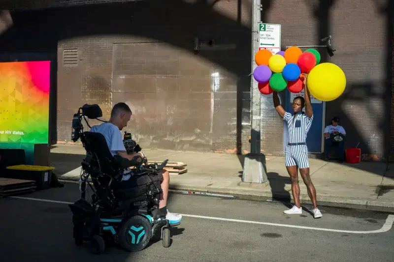 Photographer Robert Andy Coombs taking picture of person holding colorful balloons on street
