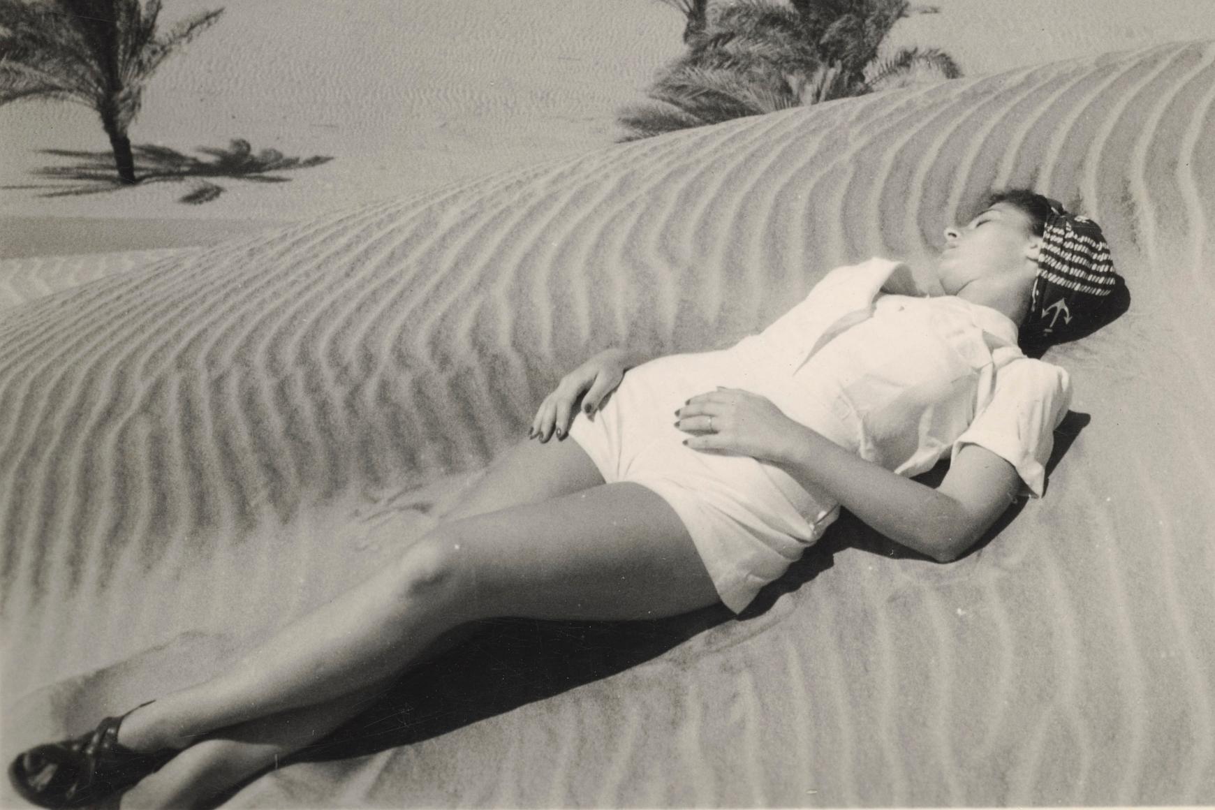 black and white photograph of person sleeping in the sand