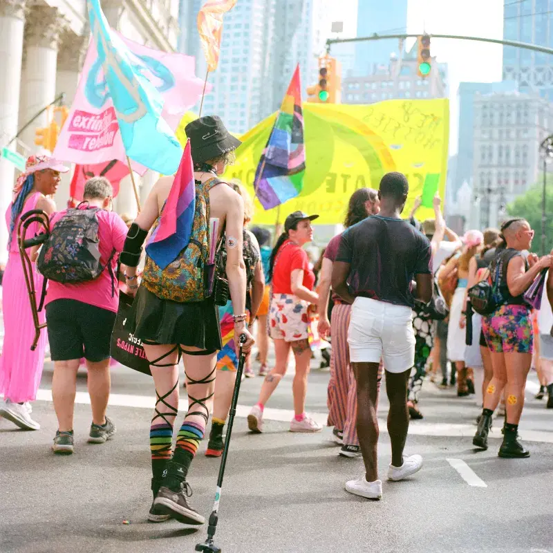 People marching on Queer Liberation March holding colorful flags