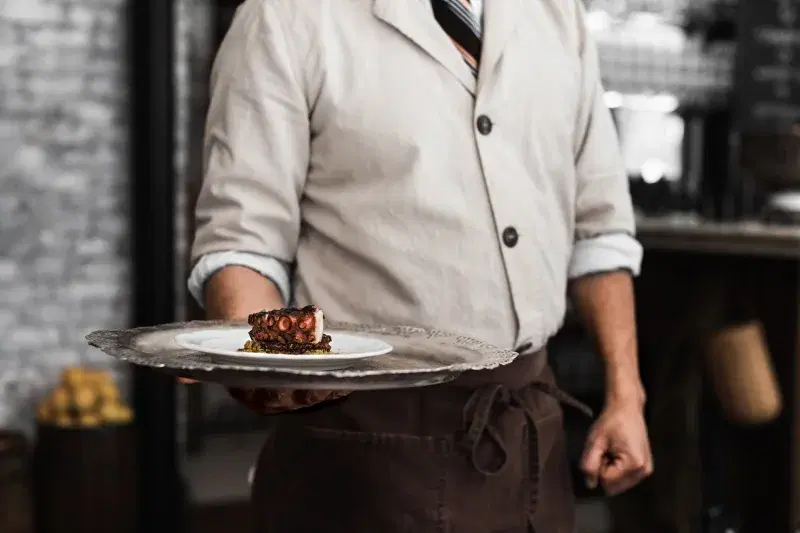 Chef holding octopus dish at Via Carota, West Village, NYC