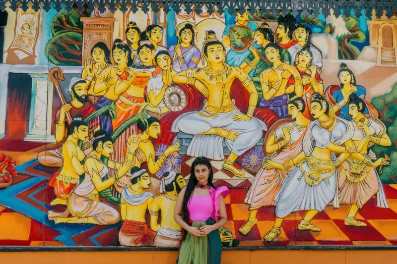 Portrait of Julia Wijesinghe, Julia is standing in front of a mural, looking at the camera