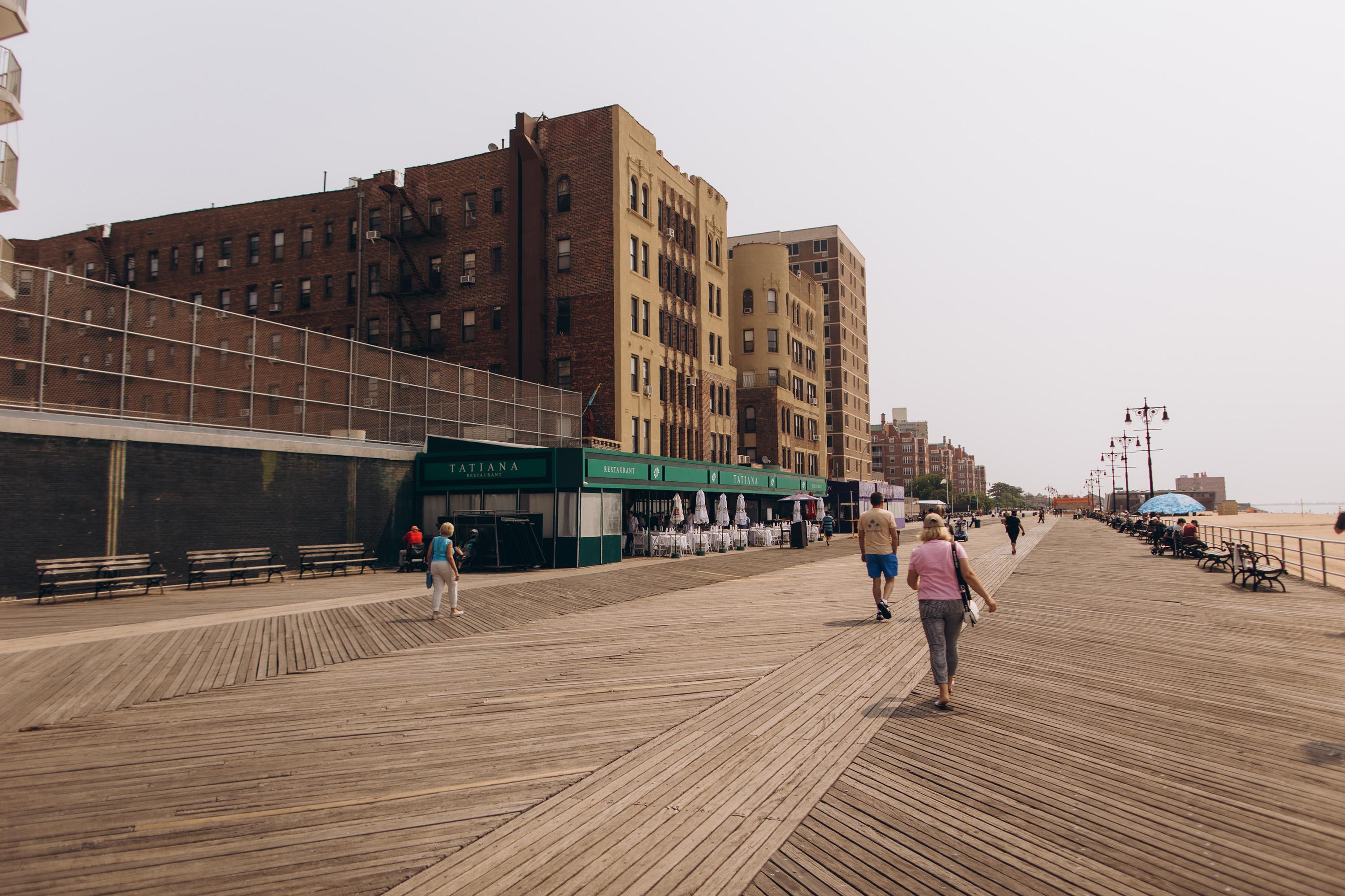 People walk at the Brighton beach boardwalk