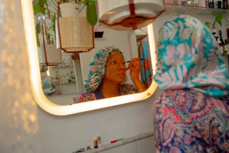 Person applying makeup in front of a mirror