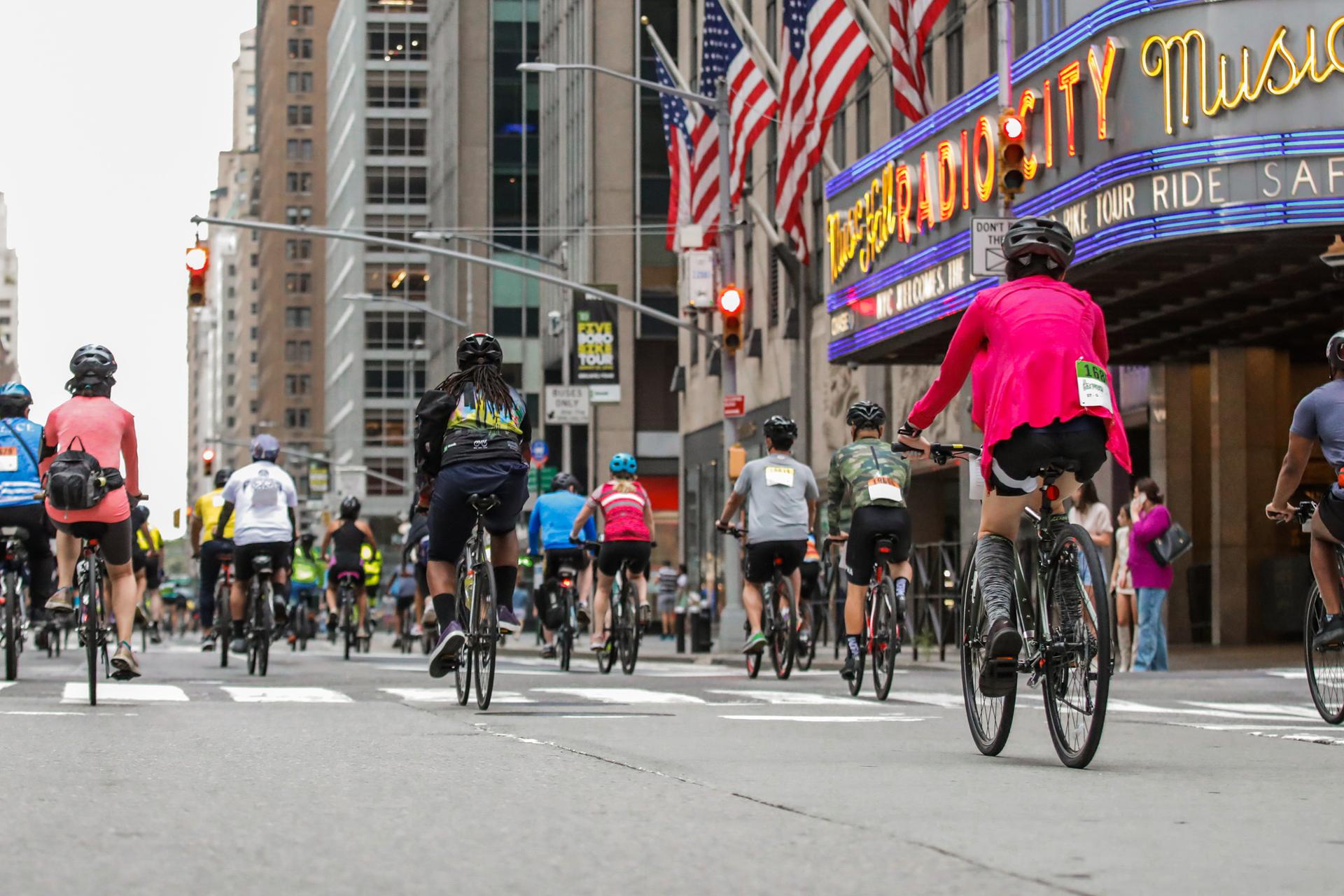 Cyclists passing in front of Radio City Music Hall, go on a tour in Manhattan, with the TD Five Boro Bike Tour
