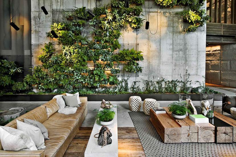 Lobby lounge of the 1 Hotel Brooklyn Bridge, featuring a plush seating area and industrial concrete backdrop, adorned with plants.
