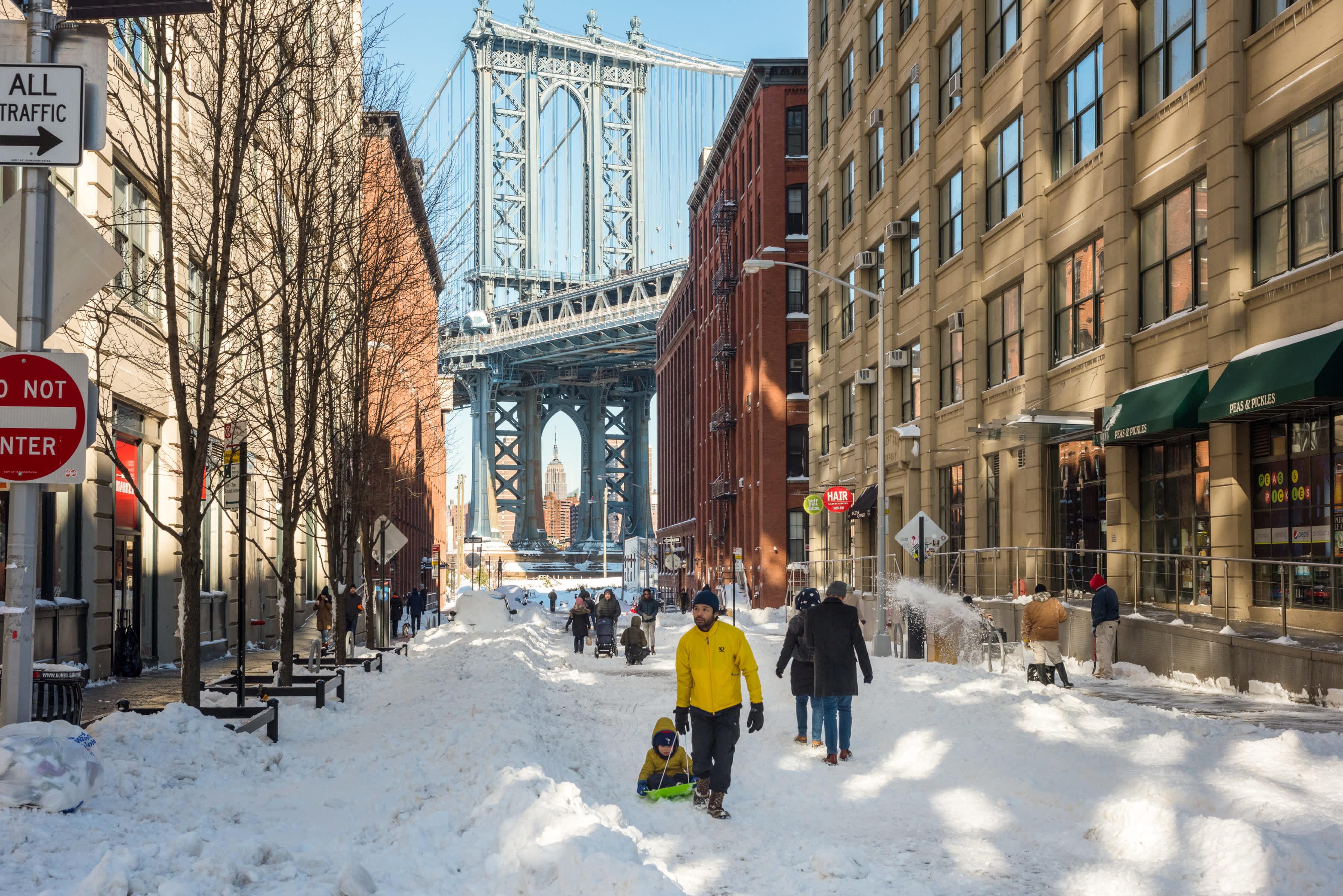 people enjoying the winter in DUMBO, during a snowstorm, manhattan bridge in the background