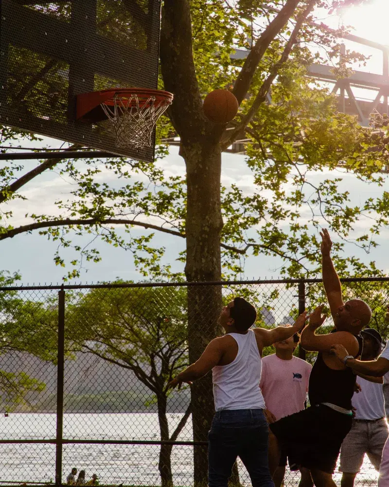 A group of people plays basketball in Astoria Park in Queens