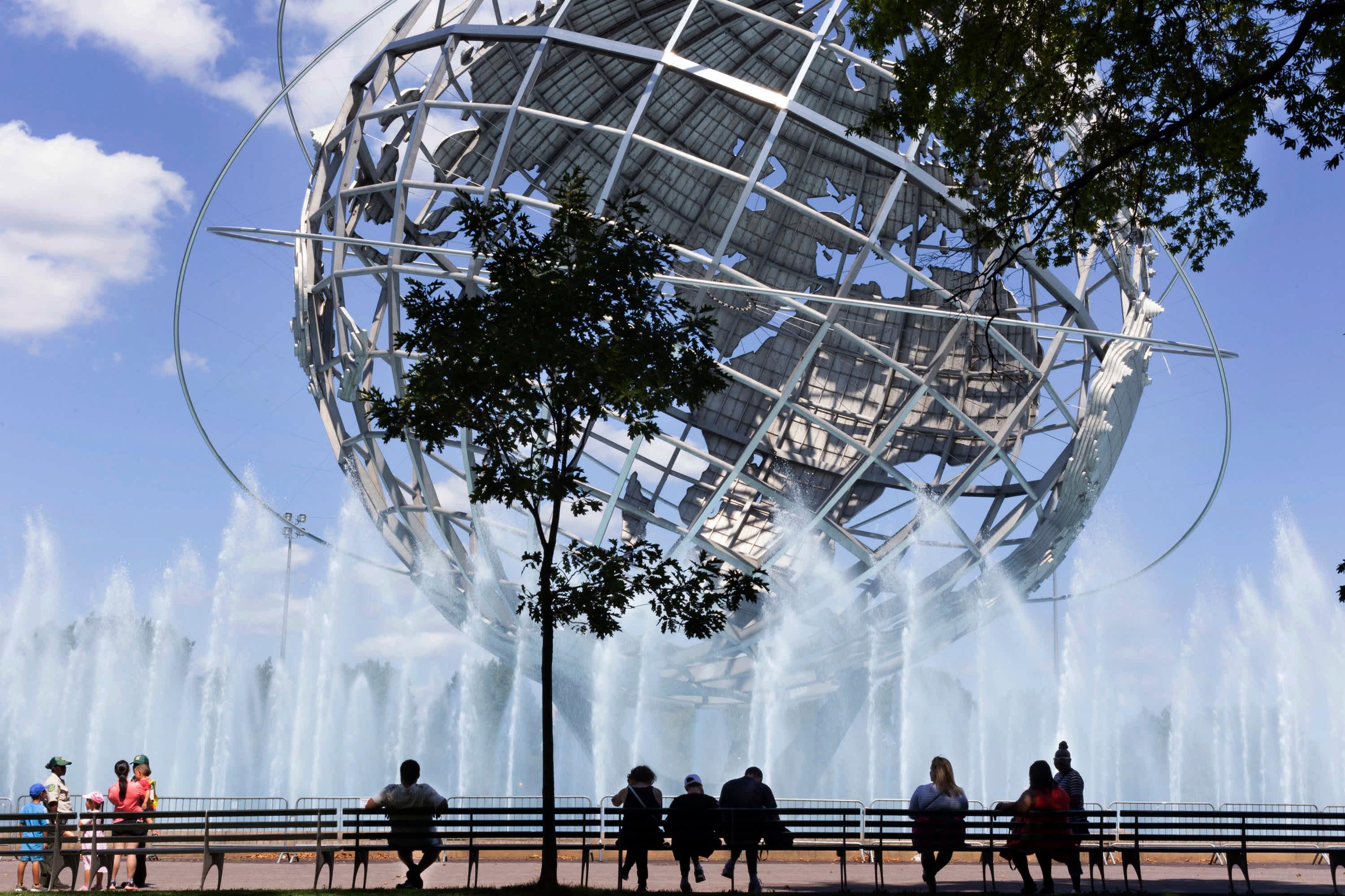 People sitting on a bench while enjoying the view of the Unisphere, steel representation of the Earth in Flushing Meadows–Corona Park, in Queens