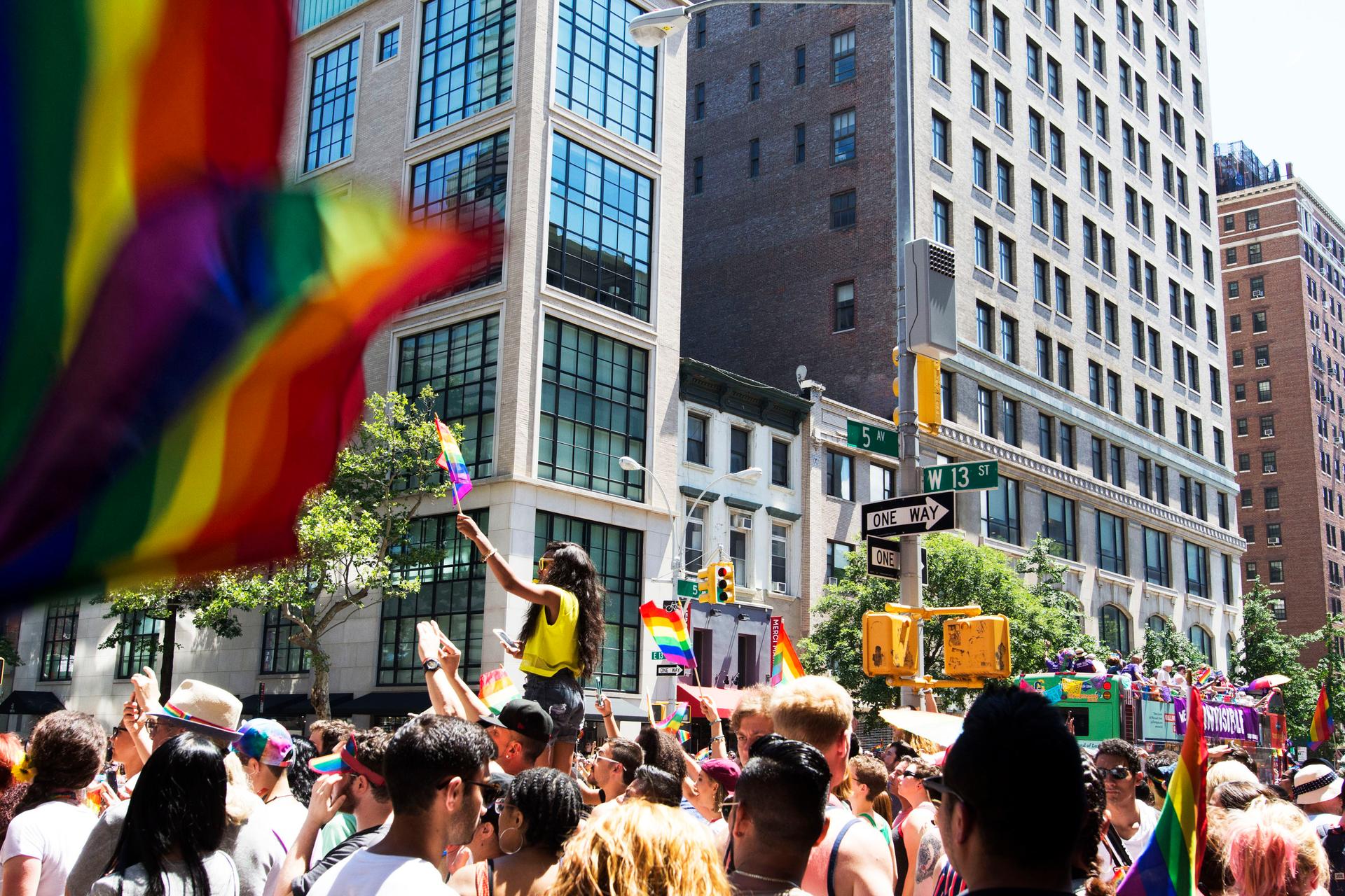 People raising LGBTQ+ Pride Flags at the Pride March, in Manhattan