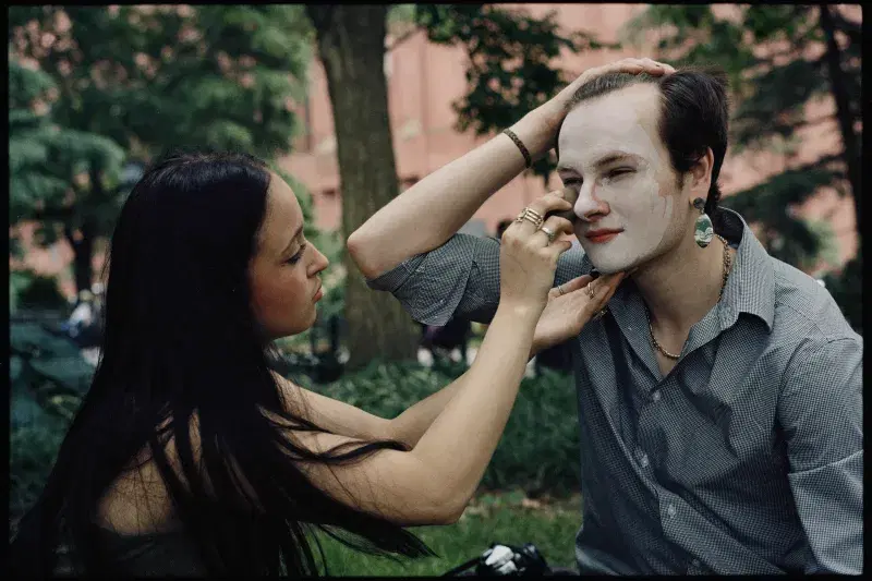 A person applies makeup on someone else face at Washington Square Park in Manhattan
