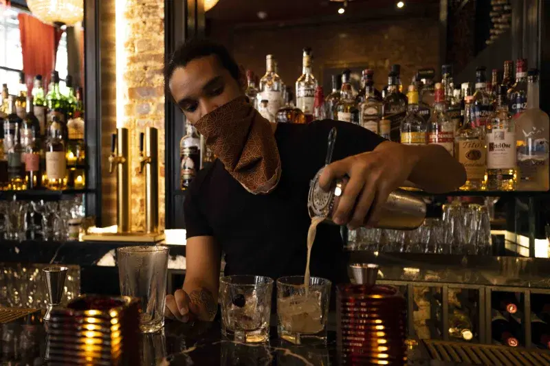 A bartender pouring a cocktail  at the bar 
