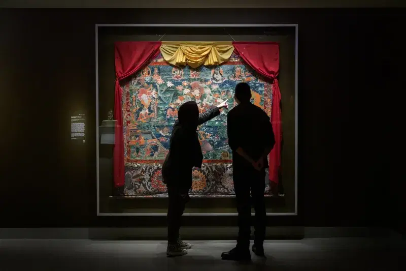a couple of people standing in front of a painting.