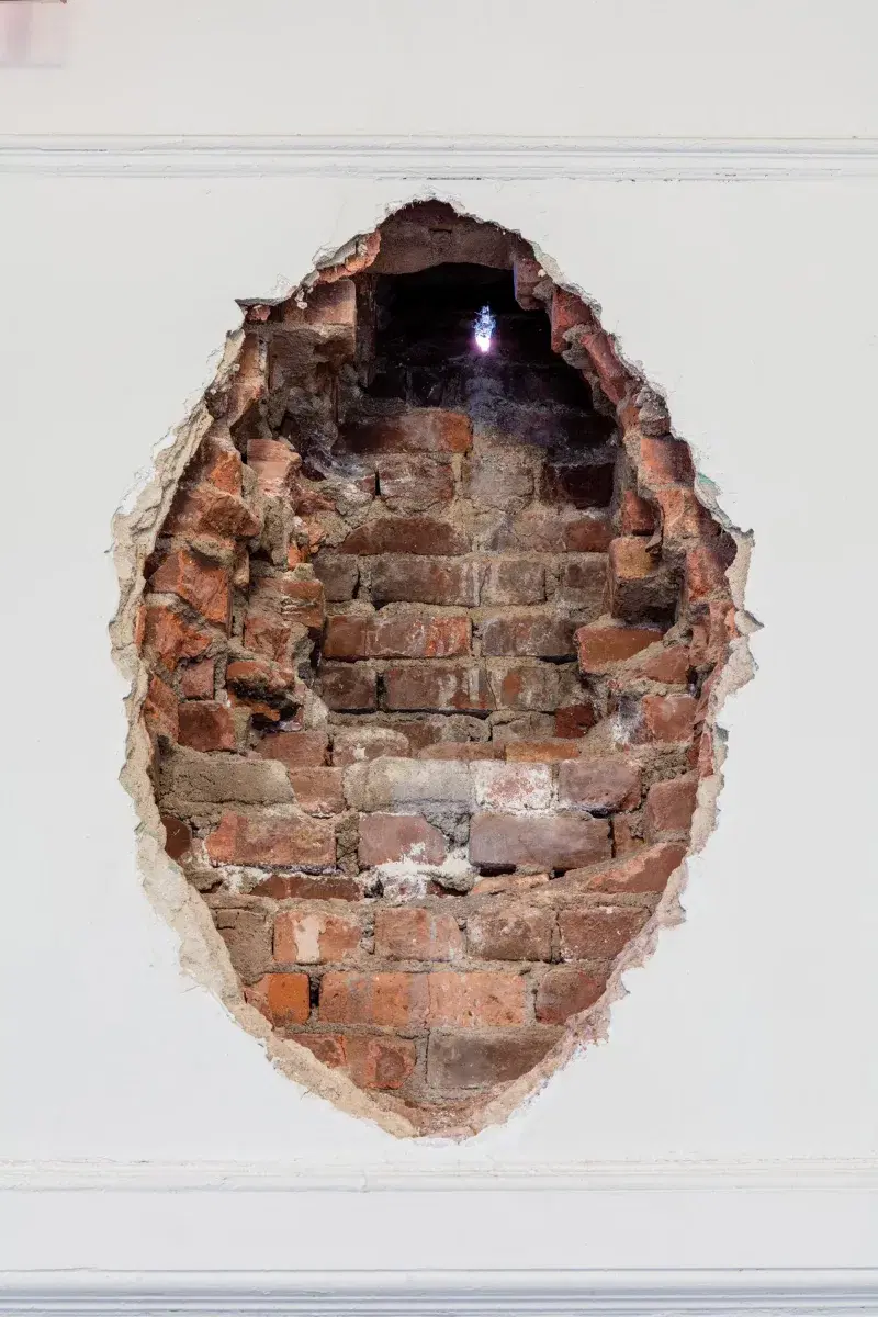 a hole in a brick wall with a light in it.